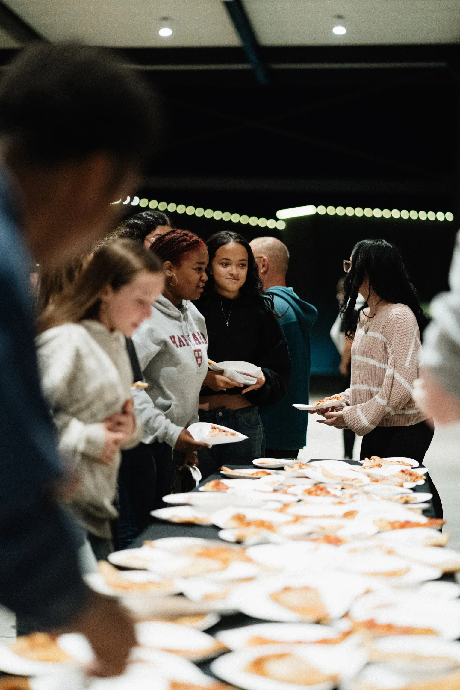 Students in line for pizza with plates lined up along a long table